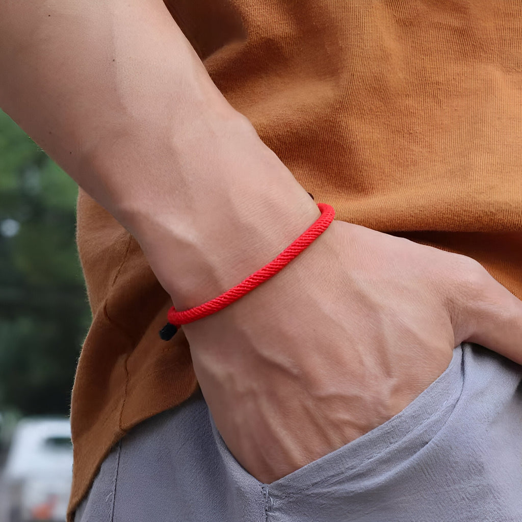 Bracelet cordon rouge simple et discret porté, style minimaliste pour homme.