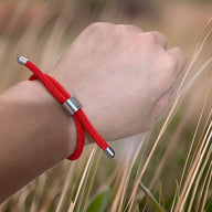 Bracelet cordon rouge simple avec embouts et perle métallique, style discret pour homme.