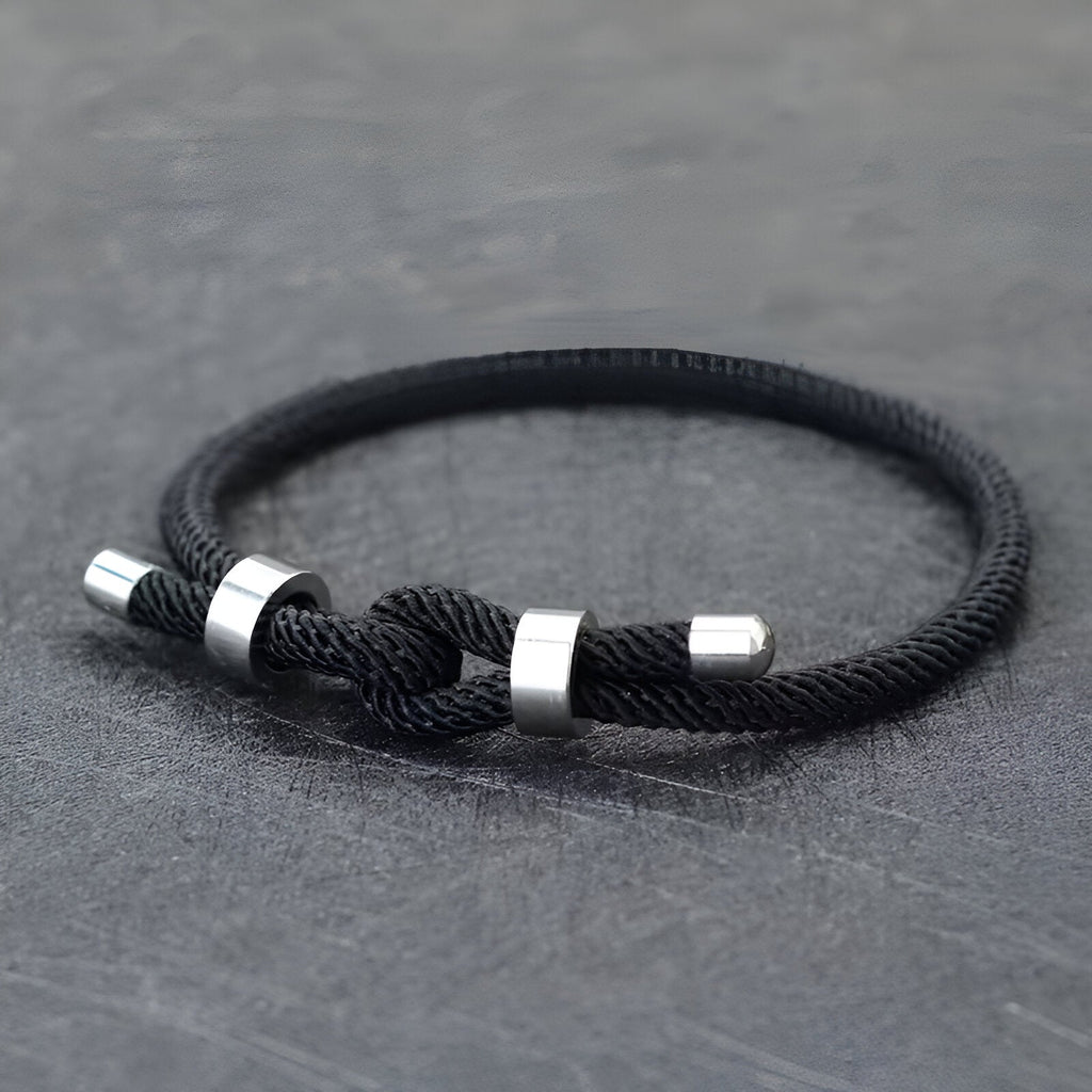 Bracelet cordon noir pour homme avec nœud et détails métalliques argentés.