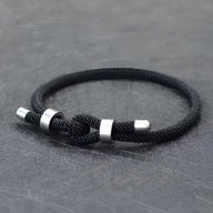 Bracelet cordon noir pour homme avec nœud et détails métalliques argentés.