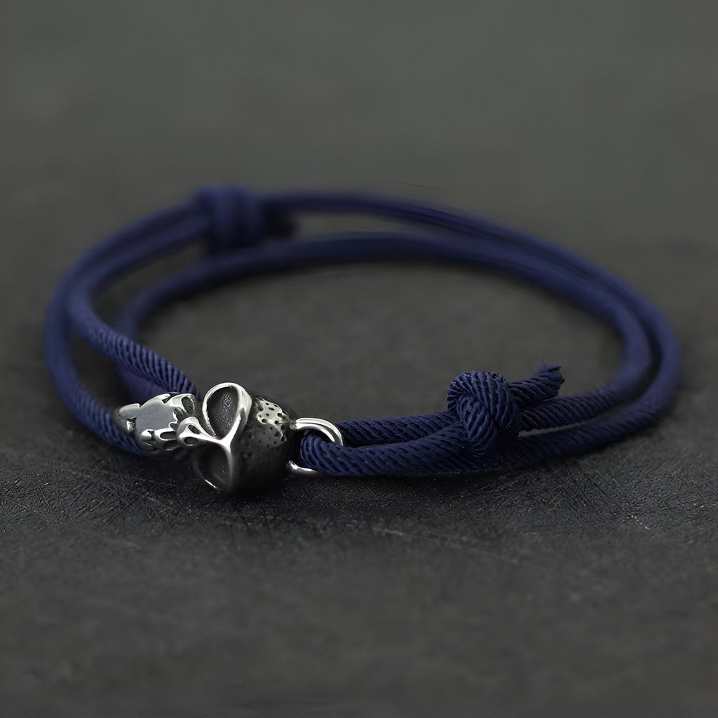 Bracelet cordon bleu marine avec tête de mort métal et perle noire mate ajustable.