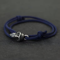 Bracelet cordon bleu marine avec tête de mort métal et perle noire mate ajustable.
