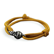 Bracelet cordon jaune avec tête de mort en métal noir et finitions gravées.