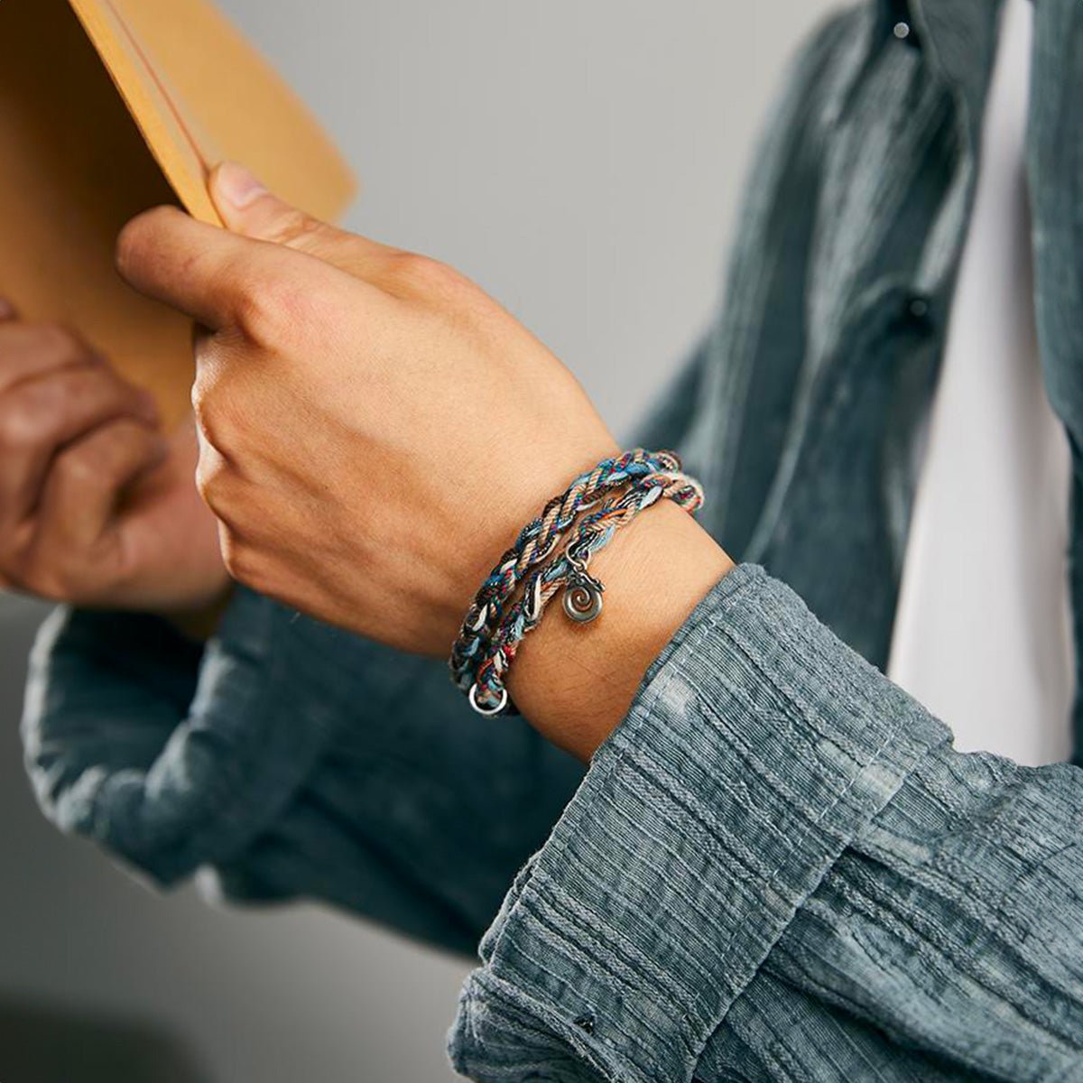 Bracelet cordon tressé multicolore avec perles œil de tigre et jade, breloques dragon et plume, fermoir crochet en métal.