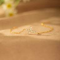Bracelet doré fin avec croix scintillante ornée de petites pierres brillantes, style délicat femme.