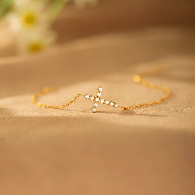 Bracelet doré fin avec croix scintillante ornée de petites pierres brillantes, style délicat femme.