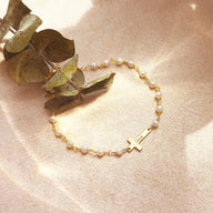 Bracelet doré avec perles d’eau douce fines et croix en acier inoxydable, style délicat et féminin.