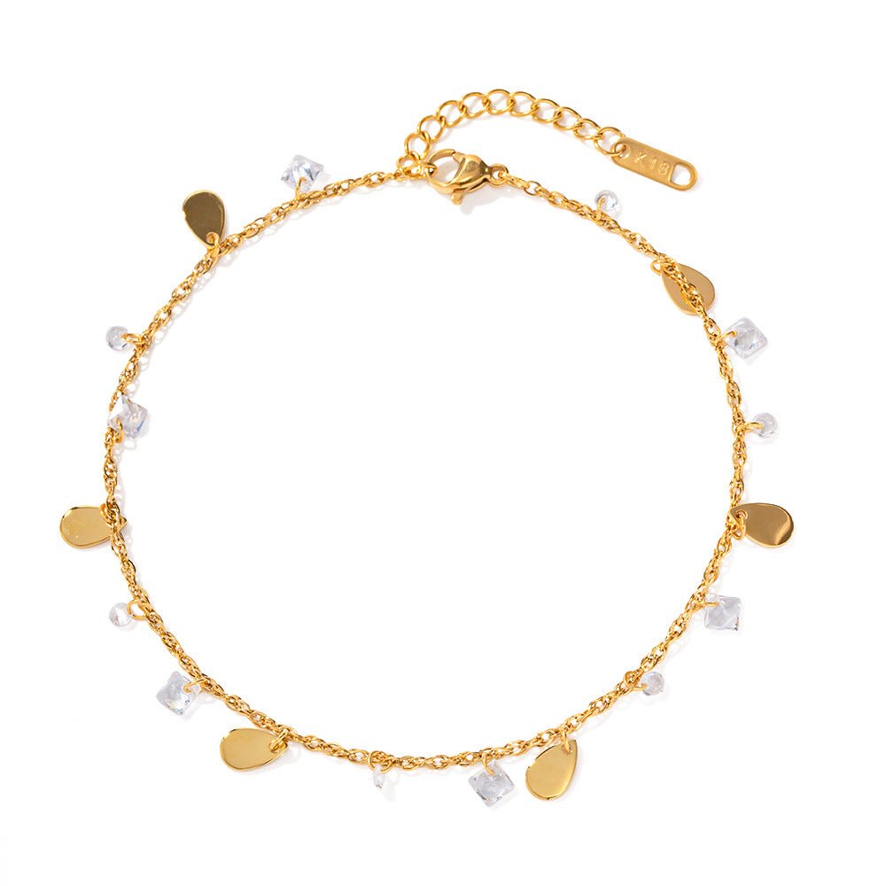 Bracelet de cheville double rang en acier doré avec cristaux et petites breloques dorées.