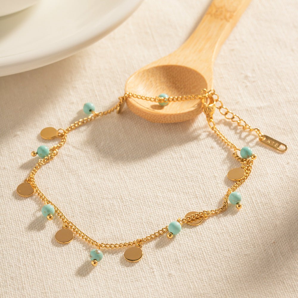 Bracelet de cheville doré à double rang avec petites turquoises et médaillons ronds élégants.