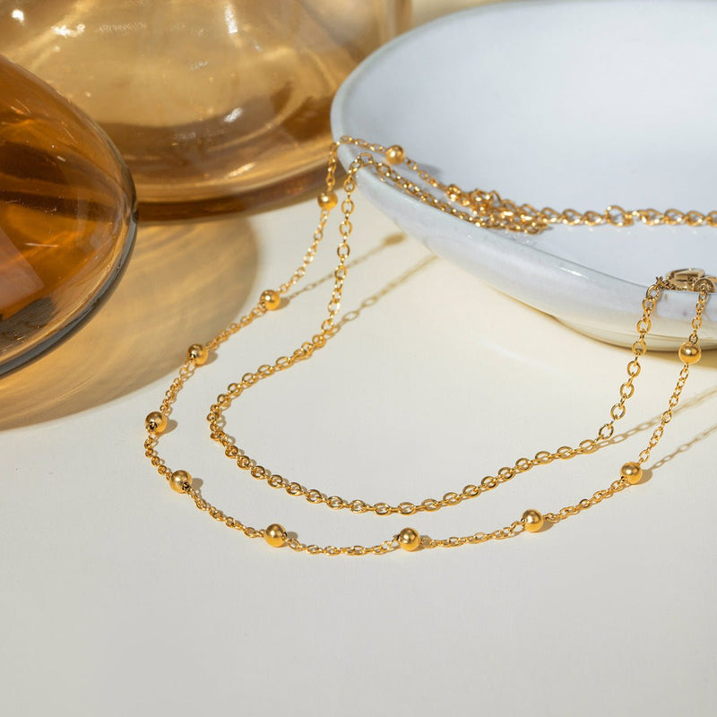 Bracelet de cheville or en acier inoxydable à double rang avec petites billes décoratives.