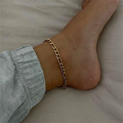 Bracelet de cheville en acier inoxydable doré, maille figaro fine, porté sur cheville féminine.