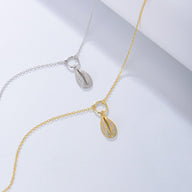 Bracelet de cheville fin en argent sterling et en or avec pendentif coquillage de mer détaillé.