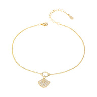 Bracelet de cheville en chaîne fine dorée avec pendentif coquillage en argent serti de petits cristaux.