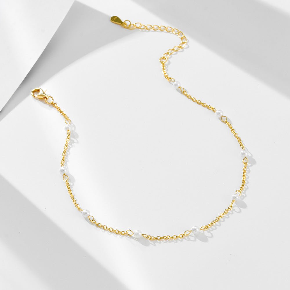 Bracelet de cheville en or avec petites perles d'eau douce blanches, chaîne fine et fermoir ajustable.