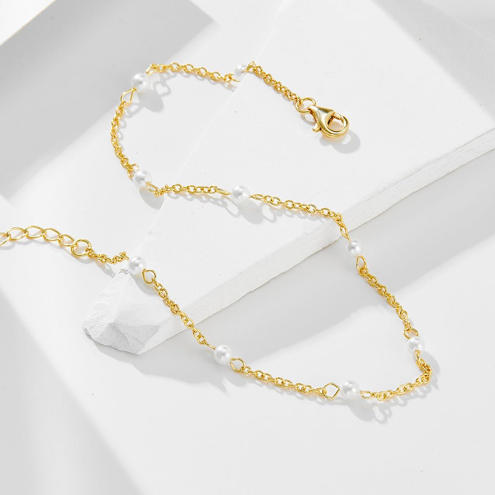 Bracelet de cheville en chaîne fine dorée avec petites perles d'eau douce blanches espacées régulièrement.