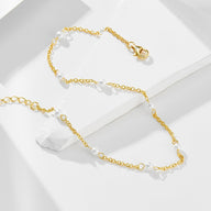 Bracelet de cheville en chaîne fine dorée avec petites perles d'eau douce blanches espacées régulièrement.