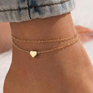 Bracelet de cheville en or fin avec double chaîne et pendentif cœur lisse.