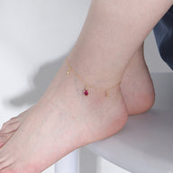 Bracelet de cheville en argent sterling avec pendentifs tortue, étoiles de mer et pierre rouge sur peau féminine.