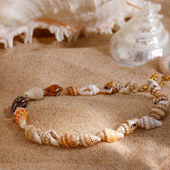 Bracelet de cheville femme en coquillages naturels multicolores sur sable fin.