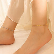 Bracelet de cheville en titane or, maille fine scintillante près de la peau et bracelet argenté délicat.