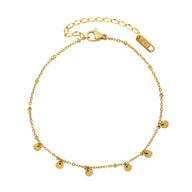 Bracelet de cheville en titane doré avec multiples petits médaillons ronds suspendus.