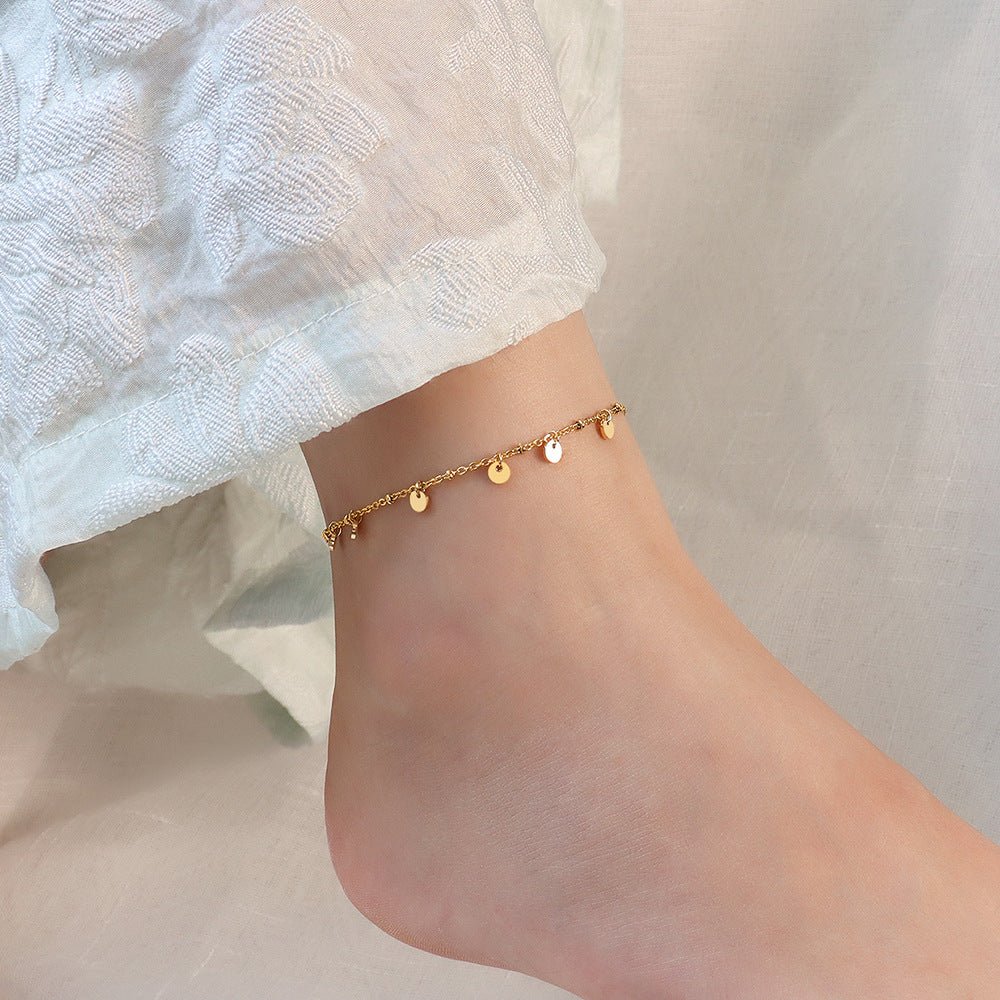 Bracelet de cheville en titane or avec multiples médaillons ronds fins, style délicat pour femme.