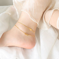 Bracelet de cheville en titane doré avec pendentifs cœur et texte « love » délicats.