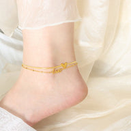 Bracelet de cheville en titane doré avec pendentifs cœur et inscription love pour femme.