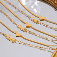 Bracelet de cheville en titane doré avec pendentifs cœur et inscription "love" délicats.