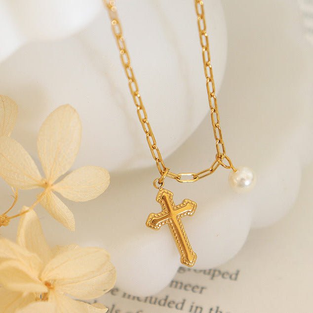 Bracelet de cheville en titane doré avec croix chrétienne ajourée et petite perle blanche.