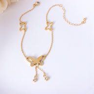 Bracelet de cheville en titane doré avec pendentif papillon et chaînes pendentifs élégantes.