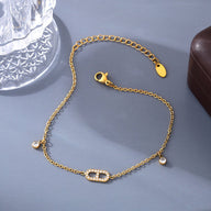 Bracelet de cheville en titane doré avec maillons fins et détail central orné de zirconiums blancs.