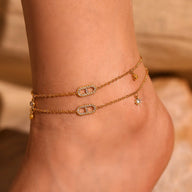 Bracelet de cheville double chaîne en titane doré avec zirconiums et petits pendentifs étoile et clé.