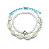 Bracelet de cheville blanc avec perles, coquillages, lien bleu et pendentif tortue en métal argenté.