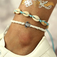 Bracelet de cheville blanc en perles avec motif tortue métal et coquillages naturels.
