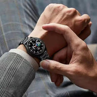 Bracelet de montre connecté noir en acier inoxydable à maillons, porté sur poignet masculin.