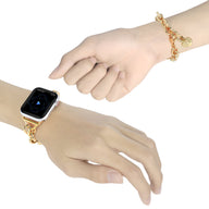 Bracelet chaîne doré avec pendentif cœur attaché à une Apple Watch or rosé sur poignet féminin.