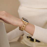 Bracelet Apple Watch doré à motifs cœurs, style élégant et féminin, porté au poignet.