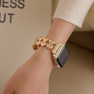 Bracelet Apple Watch doré à motif cœurs, style élégant, porté au poignet féminin.