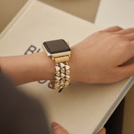 Bracelet Apple Watch or rosé à motif cœurs tressés porté au poignet féminin.