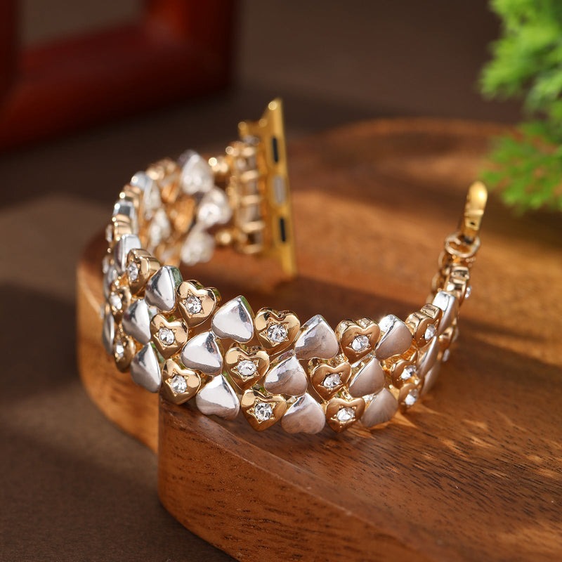 Bracelet Apple Watch or rosé avec motifs cœurs nacrés et maillons métalliques brillants pour femme.