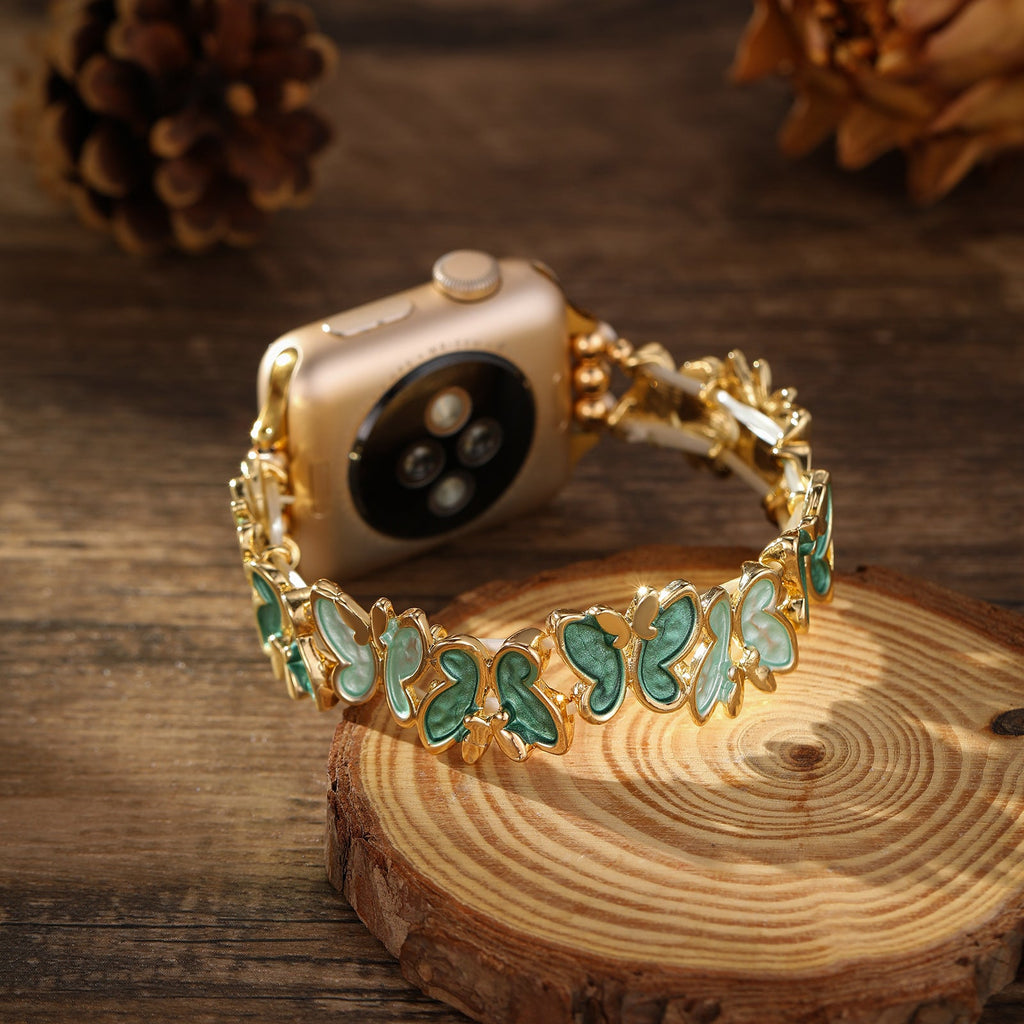 Bracelet Apple Watch doré avec motif papillons verts en émail, style élégant et féminin.