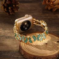Bracelet Apple Watch doré avec motif papillons verts en émail, style élégant et féminin.