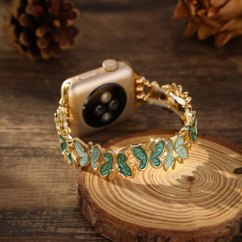 Bracelet Apple Watch doré avec motif papillons verts en émail, style élégant et féminin.