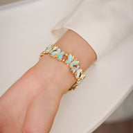 Bracelet Apple Watch doré avec motif papillons bleus et blancs, style élégant pour femme.