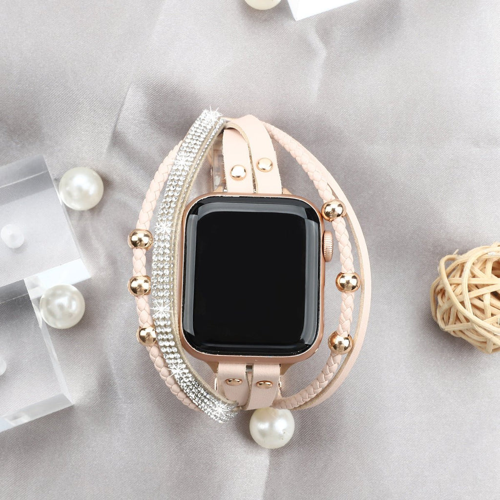 Bracelet Apple Watch rose avec strass et perle décorative, style double tour élégant.