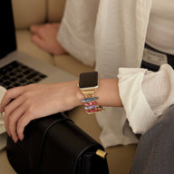 Bracelet coloré pour Apple Watch avec maillons minces et design élégant, porté au poignet féminin.