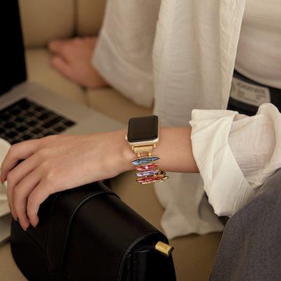 Bracelet coloré pour Apple Watch avec maillons minces et design élégant, porté au poignet féminin.