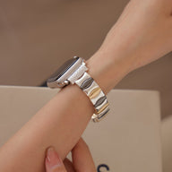 Bracelet métallique argenté pour Apple Watch, style maillons larges et brillants, porté au poignet féminin.
