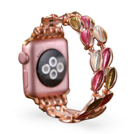 Bracelet pour Apple Watch en métal rose avec pétales scintillants roses, verts et transparents en forme de fleurs.